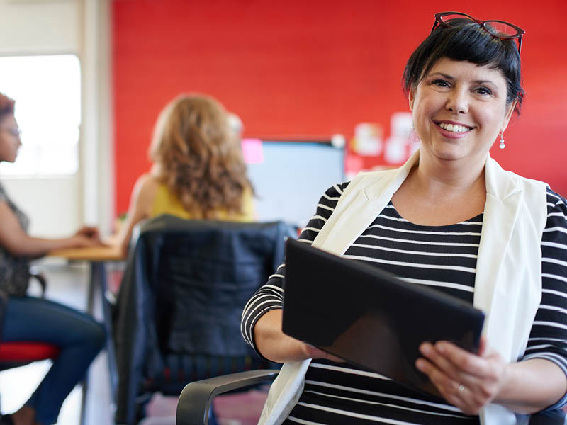 Teacher holding iPad and smiling
